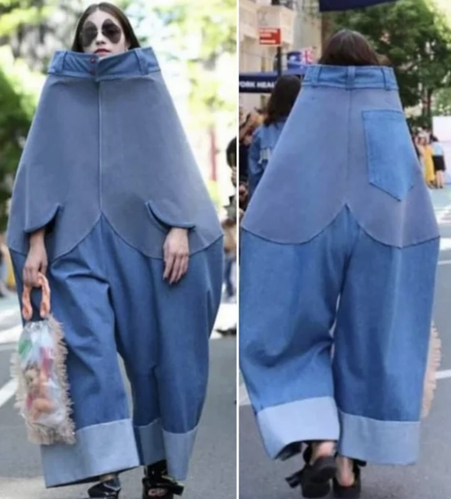 Two views of a person wearing an oversized, avant-garde denim outfit. The front features a high collar and wide pants, while the back shows a single large back pocket and wide leg openings. The individual carries a clear, ruffled bag and walks on a city street.