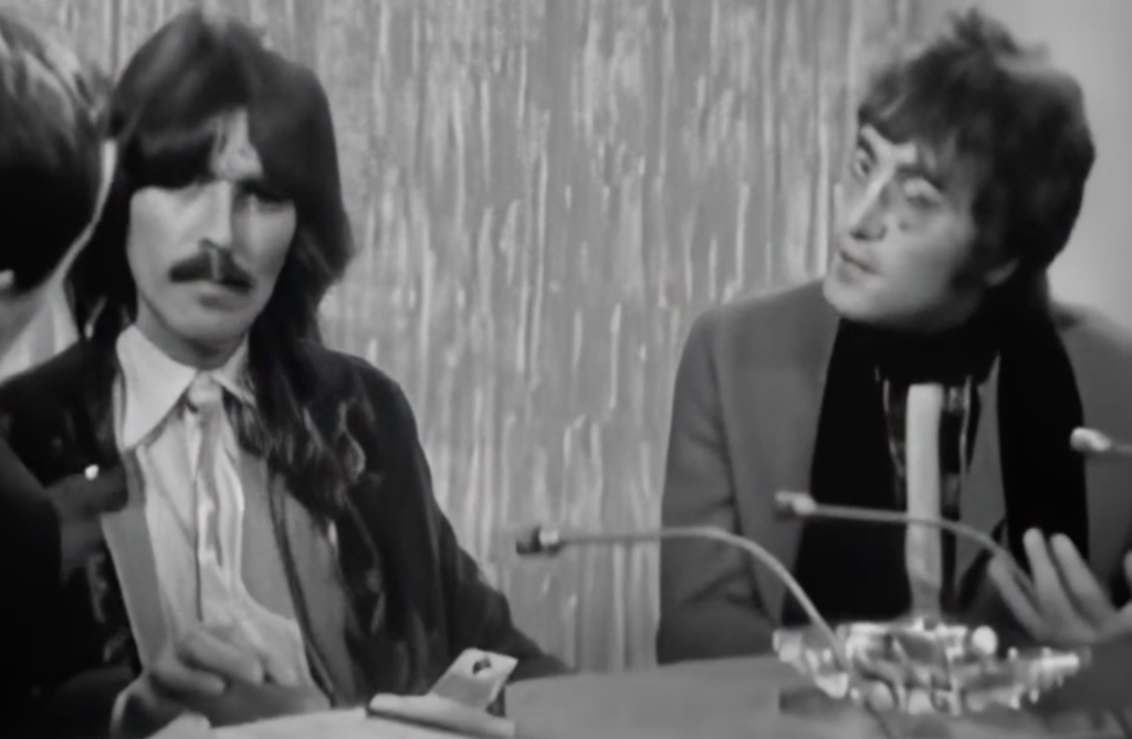 A black and white image of John Lennon being interviewed. 