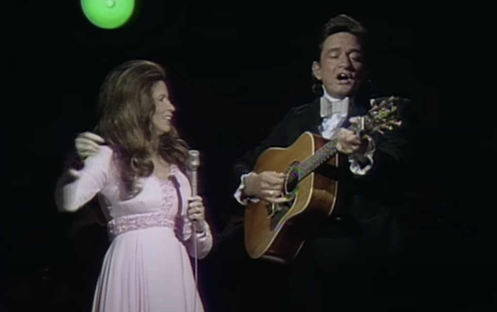 Johnny Cash holding guitar during a duet. 