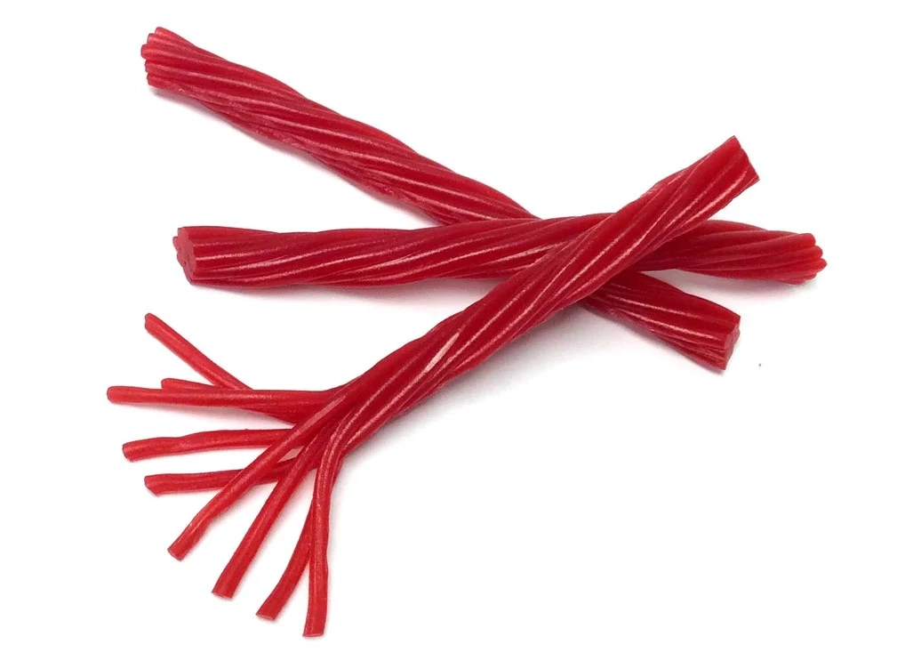 Three red licorice twists are lying on a white background. One twist is intact, while another has its ends split into several strands. The third twist is partially underneath the other two.