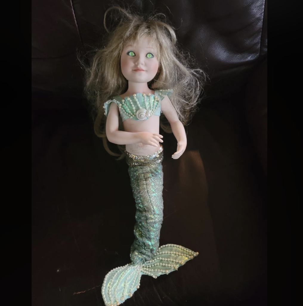 An image of a scary looking mermaid doll. 