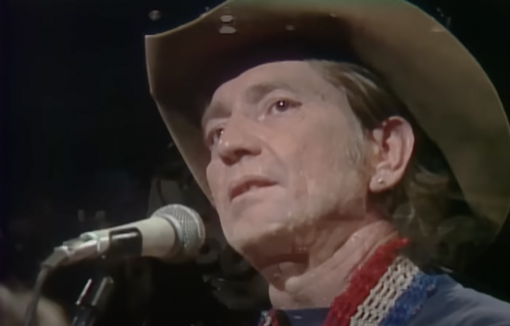A close-up still image of Willie Nelson in a cowboy hat. 