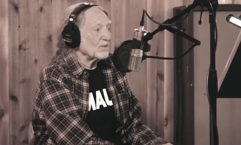 An image of Willie Nelson singing in studio. 