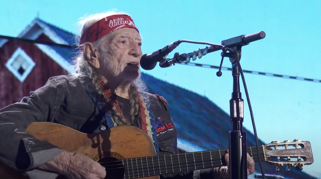 An image of Willie Nelson playing guitar. 