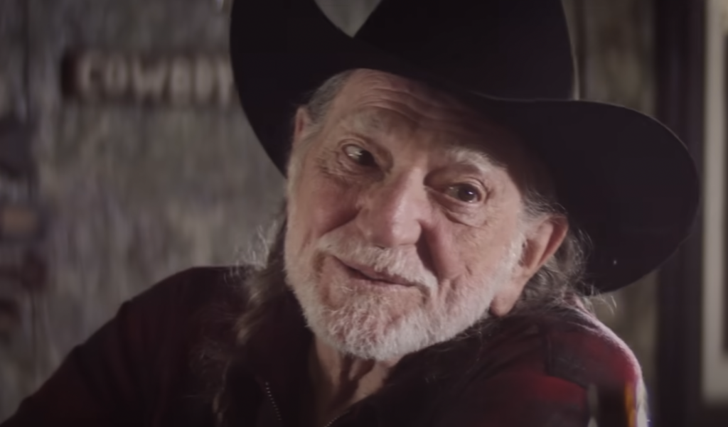 Willie Nelson in hat smiling. 