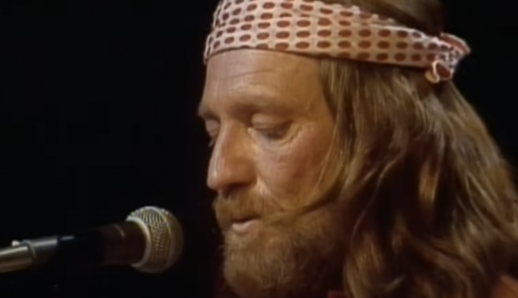 An image of a young Willie Nelson singing. 