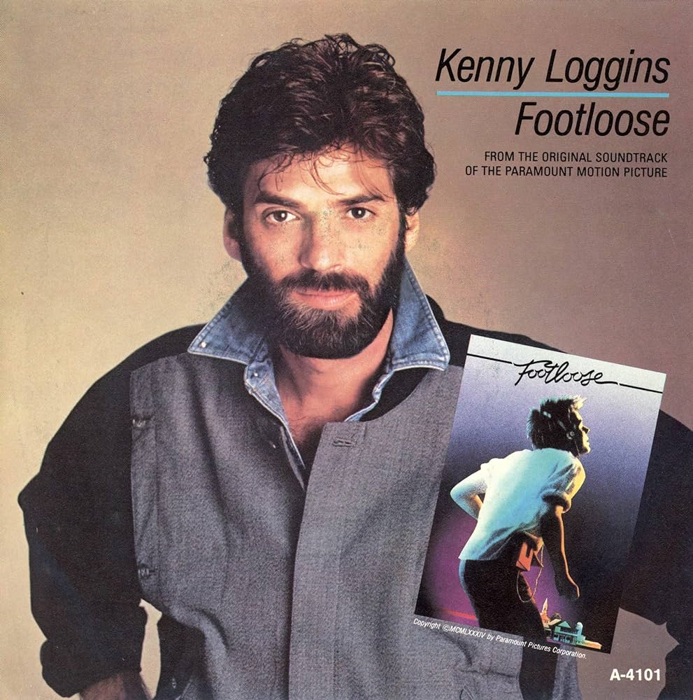 The image is an album cover for the single "Footloose" by Kenny Loggins. It features a photo of Kenny Loggins with a beard, wearing a gray and black outfit. The album cover includes text and a smaller image of a person dancing with the title "Footloose.