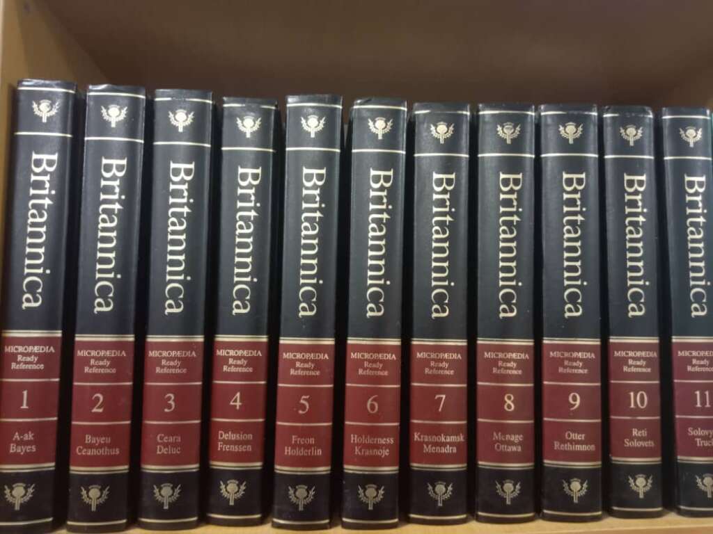 A set of eleven Encyclopædia Britannica volumes neatly arranged on a shelf in numerical order from 1 to 11. Each volume has a title in gold letters on the spine, with additional smaller text indicating specific subjects within each volume.