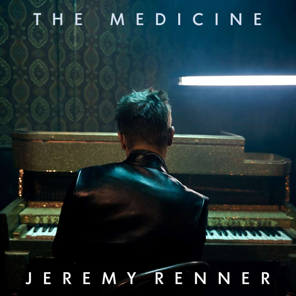 A person with short hair, wearing a black leather jacket, faces away from the camera and sits at a piano in a dimly lit room. The text "THE MEDICINE" is at the top and "JEREMY RENNER" is at the bottom of the image.
