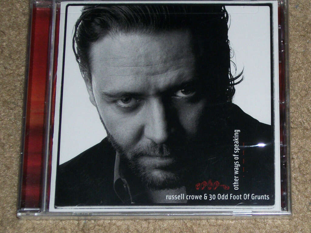 A close-up image of a CD titled "Other Ways of Speaking" by Russell Crowe & 30 Odd Foot of Grunts. The cover features a black-and-white portrait of Russell Crowe looking directly into the camera with a serious expression. The background is white with text.