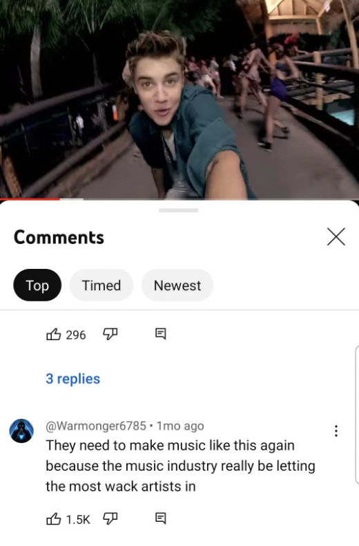 A young man wearing a green shirt is taking a selfie-style video on a bridge, with people walking in the background. A YouTube comment below by user @Warmonger6785 reads: "They need to make music like this again because the music industry really be letting the most wack artists in." The comment has 1.5K likes, 296 responses, and has been up for 1 month.