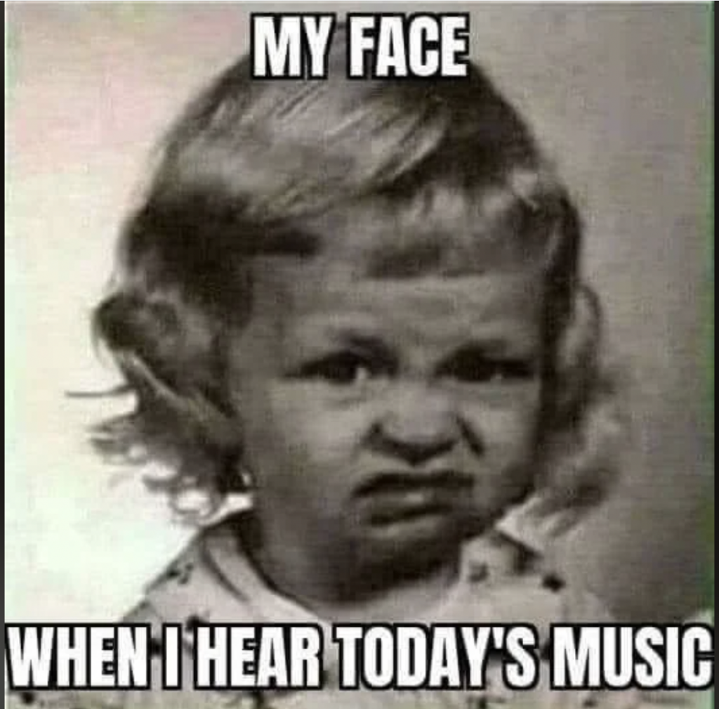 Black and white photo of a young child with curly hair making a disgusted facial expression. The text above and below the image reads, "MY FACE WHEN I HEAR TODAY'S MUSIC.