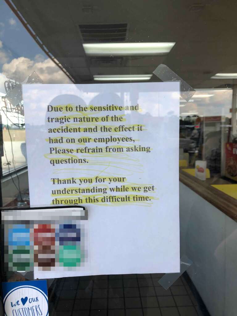 A printed sign taped to a window in a store reads, "Due to the sensitive and tragic nature of the accident and the effect it had on our employees, Please refrain from asking questions. Thank you for your understanding while we get through this difficult time.