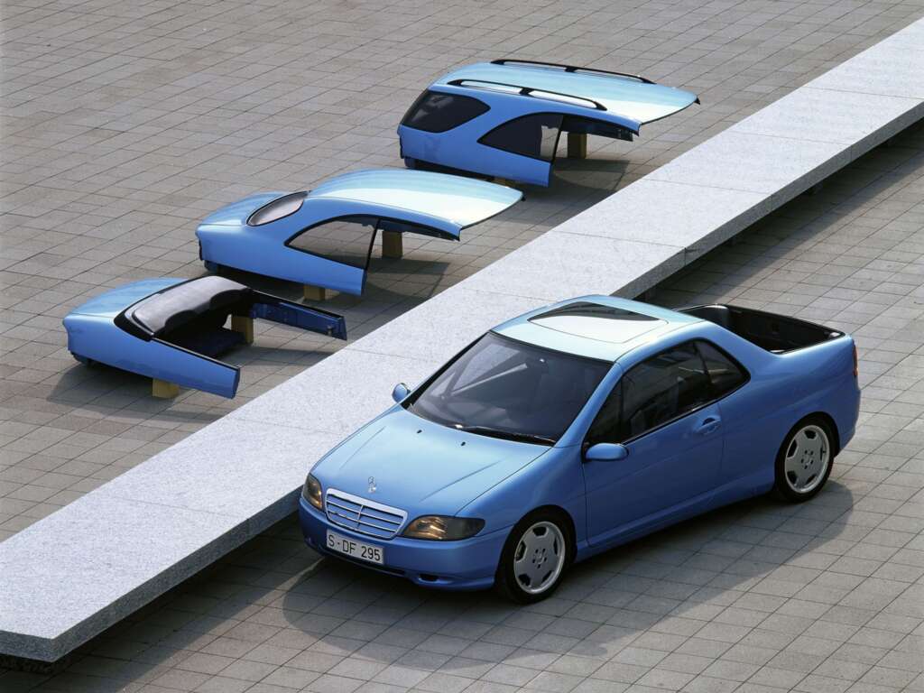 A blue car is parked on a tiled surface next to several separated roof components arranged on a bench. The components include different roof styles and rear sections, showcasing various customization options for the car.