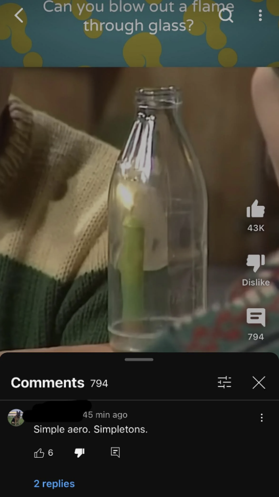 A lit candle is placed inside a clear glass bottle. The scene is paused on a YouTube video with 794 comments, 43K likes, 6 likes on a user comment stating "Simple aero. Simpletons," and a person in a green and brown striped sweater visible in the background.
