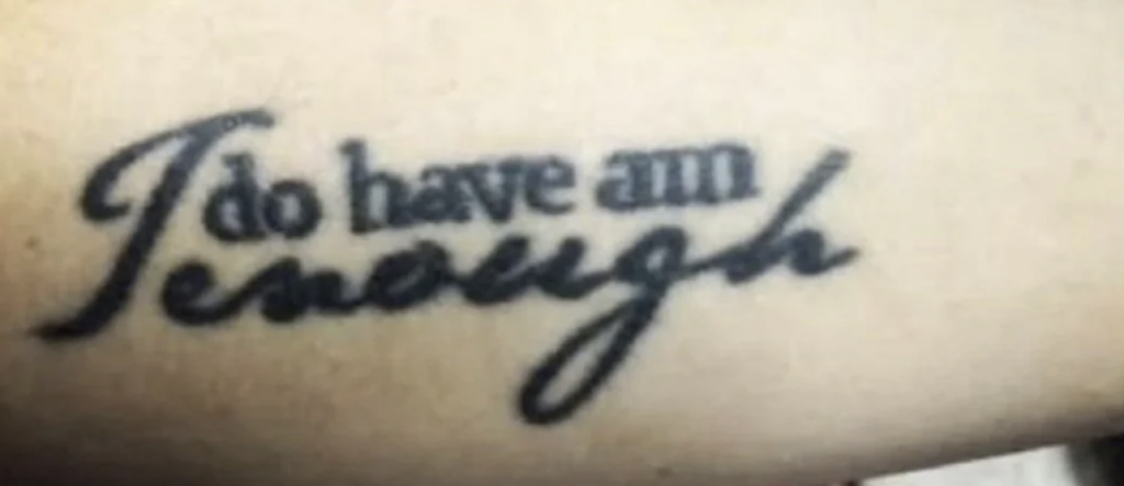 A close-up image of a tattoo with the text "I do have am enough" written in cursive script on a person's skin.