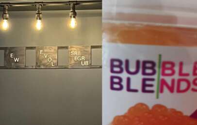 A wall art piece with Scrabble-style tiles spells out nonsensical words. Next to it, a close-up of a packaging label for "Bubble Blends" with orange bubble tea pearls visible inside. There are three light bulbs hanging from above on a dark metal fixture.