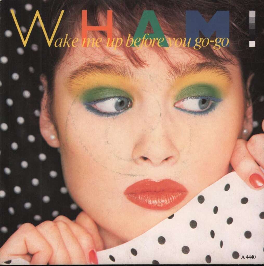 Close-up of a woman with colorful eyeshadow looking to the side. The text "Wham!" in large letters and "Wake me up before you go-go" in smaller font is displayed above her head. She is holding a polka-dotted fabric partially covering her face.