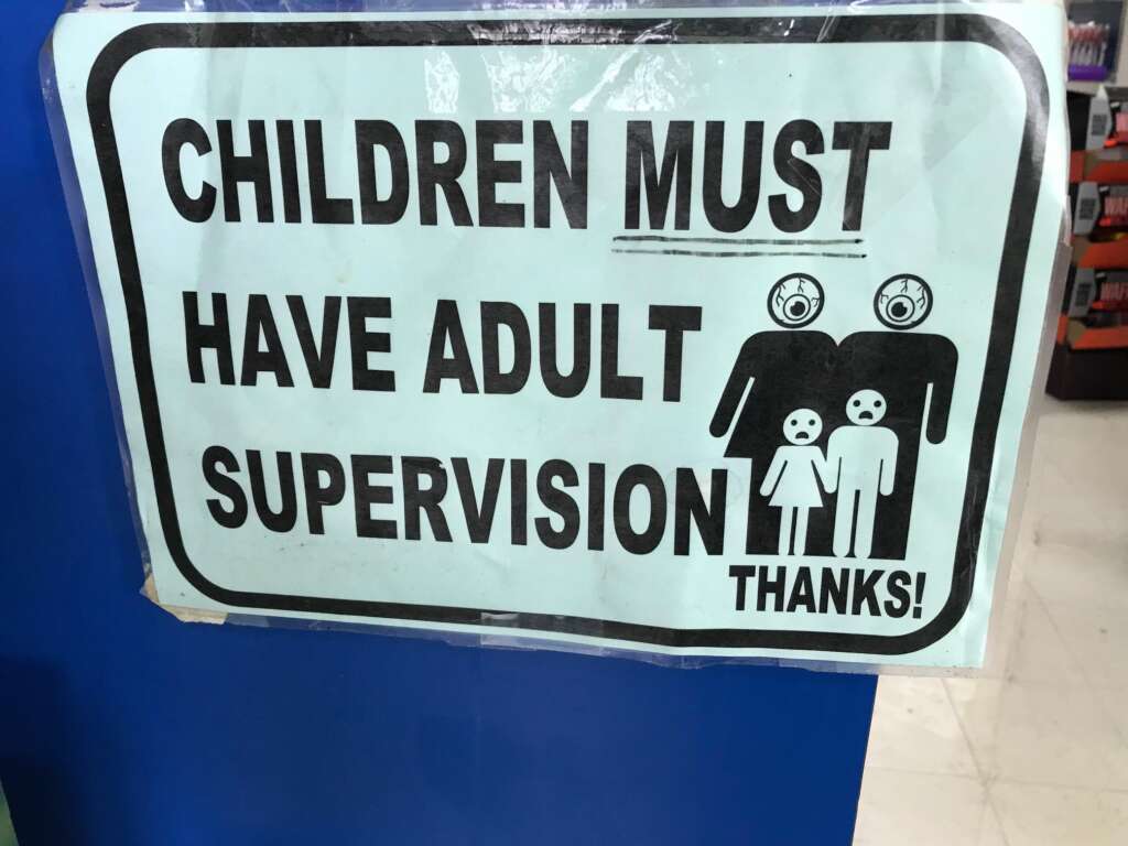 A sign reads "Children must have adult supervision. Thanks!" The sign includes a drawing of two adults and two children, all with large eyes, resembling security cameras, emphasizing the need for supervision.