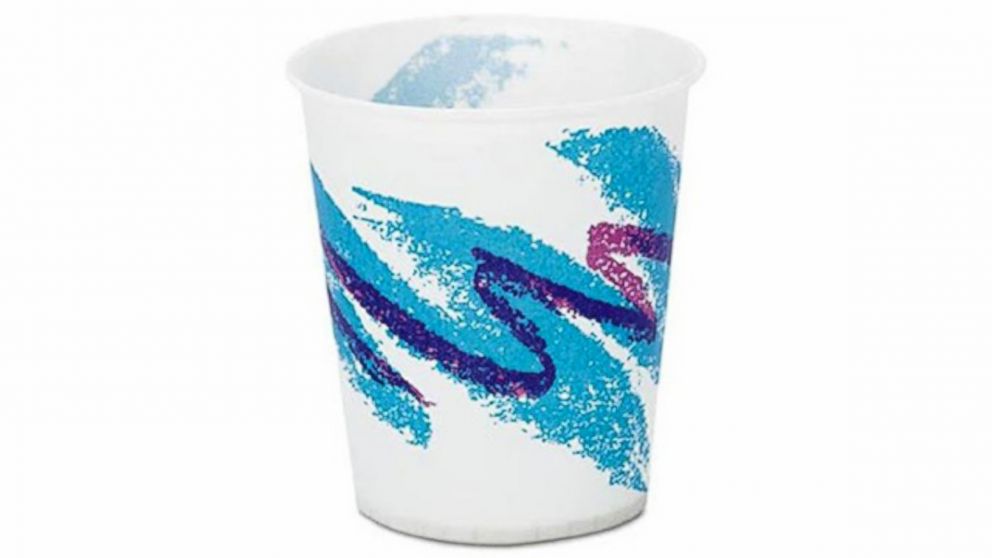 A white paper cup featuring a vintage 90s design with a blue and purple abstract swirl pattern running diagonally across the surface. The background design evokes a sense of nostalgia associated with that era.