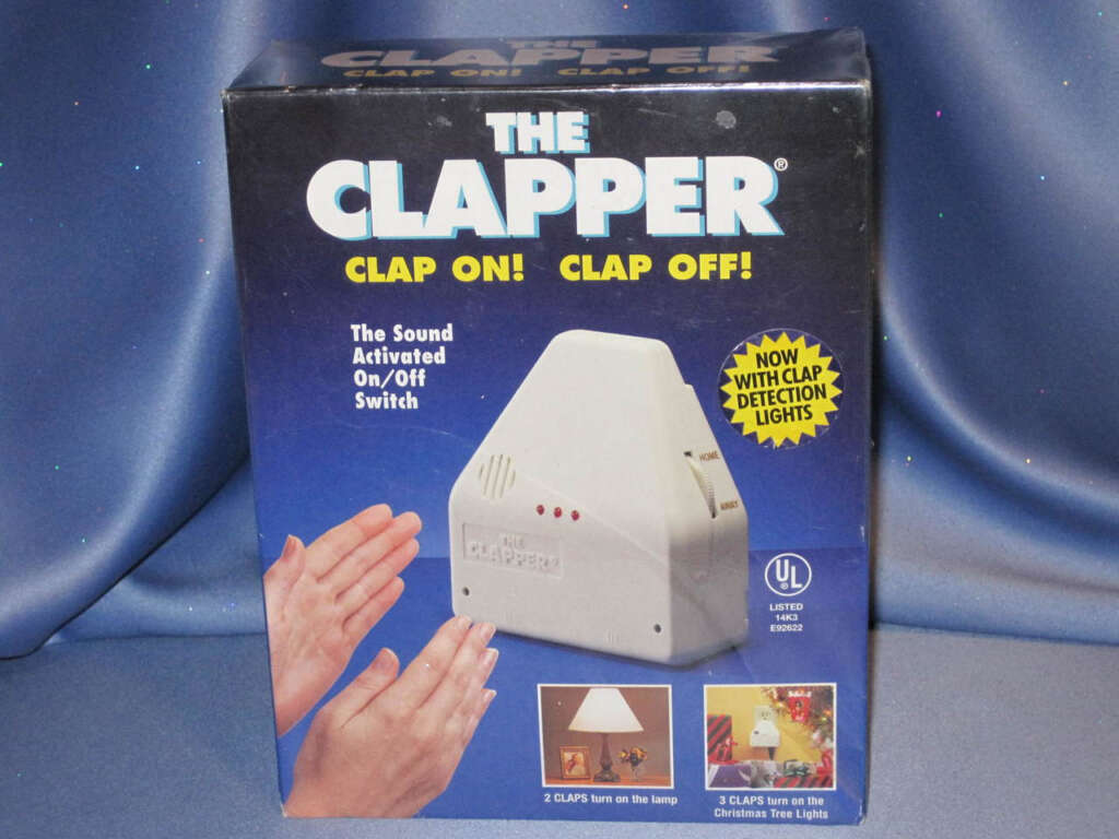The image shows a boxed "The Clapper" sound-activated on/off switch. The box features a hand clapping, indicating the device can turn appliances on or off with a clap. It mentions "CLAP ON! CLAP OFF!" and shows lights indicating detection. UL Listed logo is displayed.