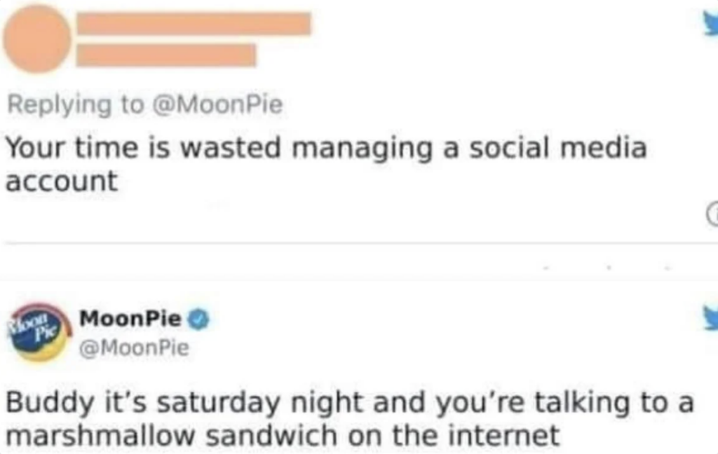 A tweet reply exchange where a user criticizes MoonPie for wasting time managing a social media account. MoonPie responds humorously, pointing out that it's a Saturday night and the user is talking to a marshmallow sandwich on the internet.