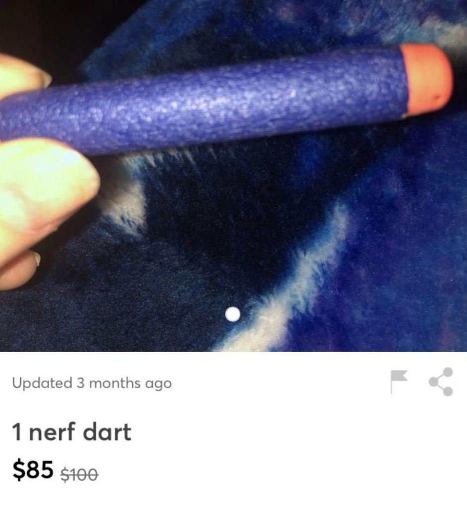 A close-up photo of a single blue Nerf dart with an orange tip, held in a person's fingers against a blue and white fabric background. The listing price is $85, previously $100. The update note indicates the listing was updated 3 months ago.