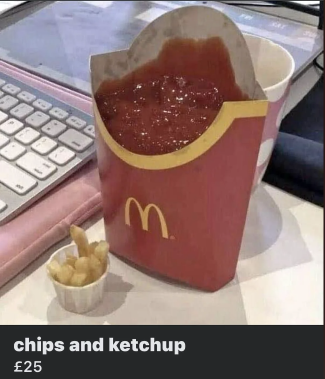 A box of McDonald's fries is filled to the top with ketchup, placed on a table next to a small white container holding a few fries, a keyboard, and a paper cup. The caption below reads "chips and ketchup £25".