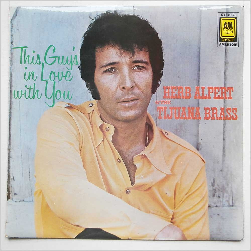 Album cover for "This Guy's in Love with You" by Herb Alpert & The Tijuana Brass. The image features Herb Alpert in a yellow shirt, leaning against a light-colored background. The album title is written in green and white text on the left.