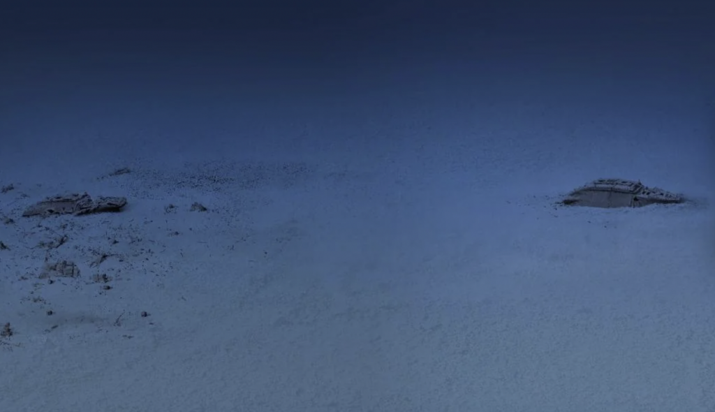 A deep underwater scene shows two large sections of a shipwreck resting on the ocean floor. The surrounding area appears to be desolate, with a blue hue illuminating the scene, emphasizing the depth and isolation of the wreckage.