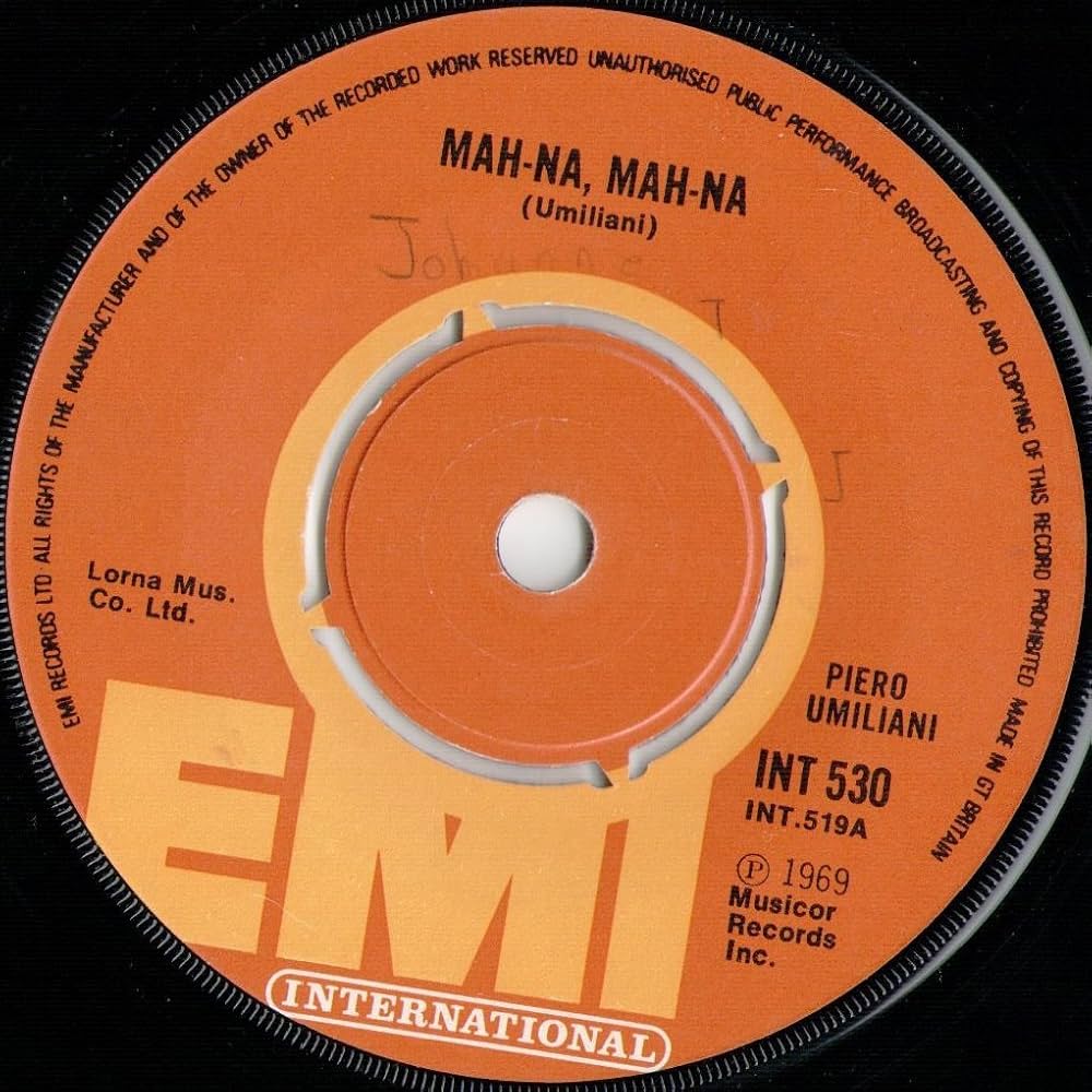 A close-up photo of a vinyl record label with the song "Mah-Na, Mah-Na (Umiliani)" by Piero Umiliani. The label is orange with black text, featuring the EMI International logo at the bottom. The record release year is 1969 and catalog number INT 530.