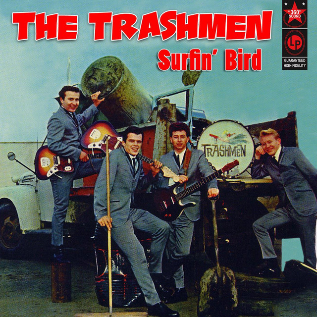 Album cover for "Surfin' Bird" by The Trashmen. Four band members in suits pose with musical instruments and a makeshift cannon mounted on a vehicle. The band's name and album title are prominently displayed at the top in bold red letters.