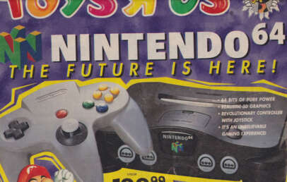 A vintage Toys R Us advertisement for the Nintendo 64. The colorful ad features the console and the controller prominently, with text highlighting "64 Bits of Pure Power," "Realistic 3D Graphics," and promoting it as "An Unbelievable Gaming Experience!" The price is $149.99.