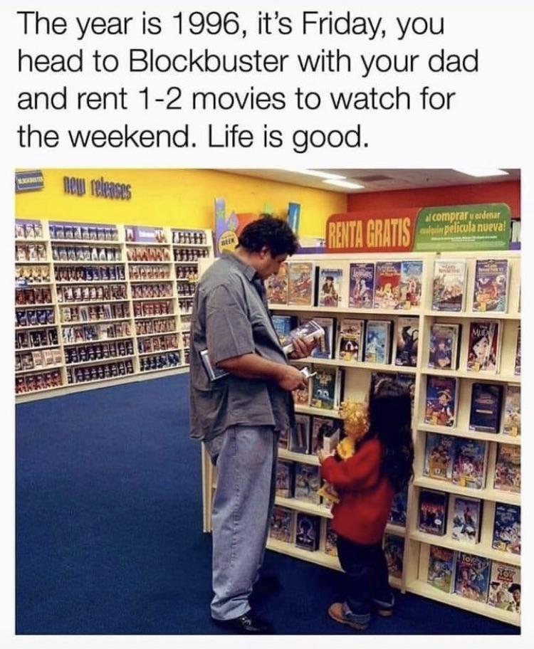 A man and a young girl are in a Blockbuster video rental store. They are browsing DVDs on shelves marked "New Releases" and "Renta Gratis" in Spanish. The man holds a DVD case, and the girl looks at the DVDs attentively. The text reads, "The year is 1996...