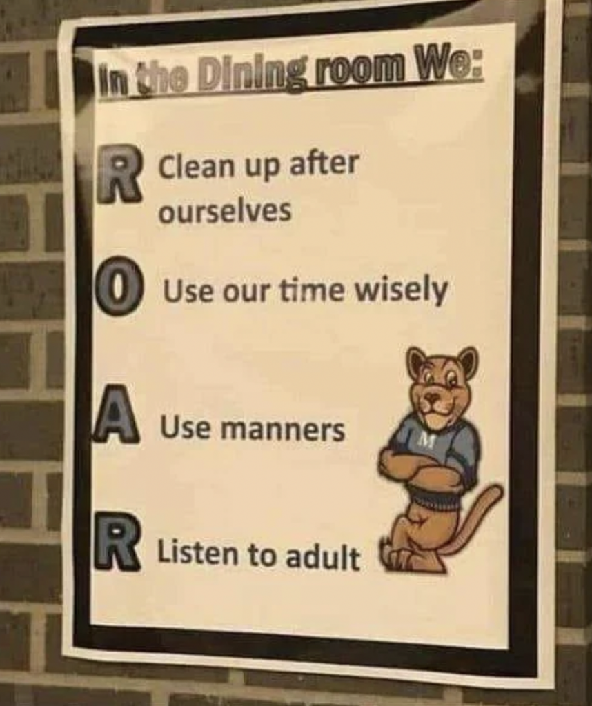 A poster on a brick wall outlines rules for the dining room. It features an acronym "ROAR": R- Clean up after ourselves, O- Use our time wisely, A- Use manners, R- Listen to adult. The poster has a cartoon image of a smiling lion in a blue shirt.