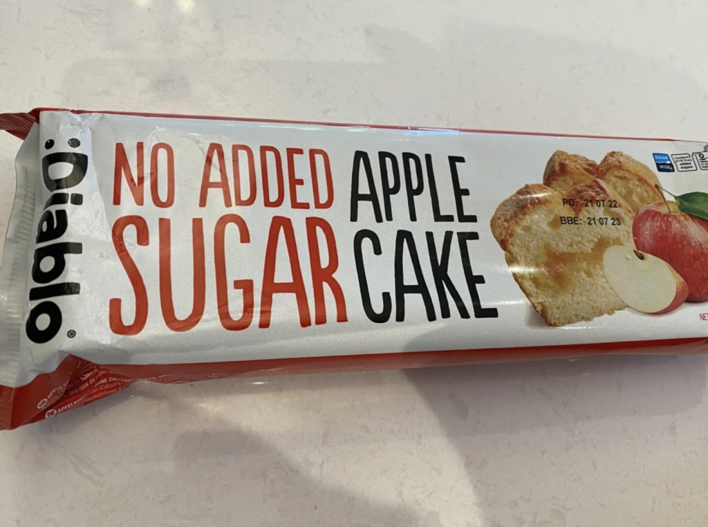 A packaged food item labeled "NO ADDED SUGAR APPLE CAKE" by the brand Diablo. The packaging is white with red accents, featuring an image of apple cake slices and whole red and green apples.