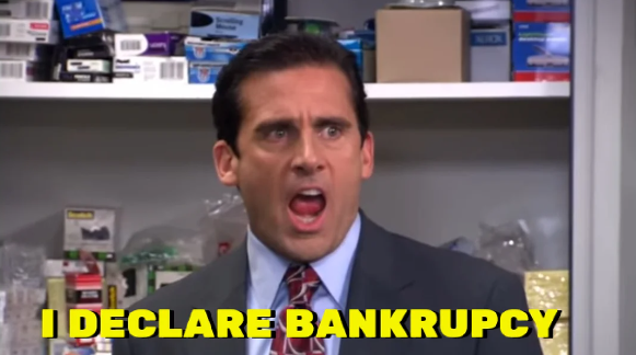 A man in a suit is standing in an office supply room, looking shocked and yelling with his mouth wide open. The caption at the bottom of the image reads, "I DECLARE BANKRUPCY" in bold, yellow letters.