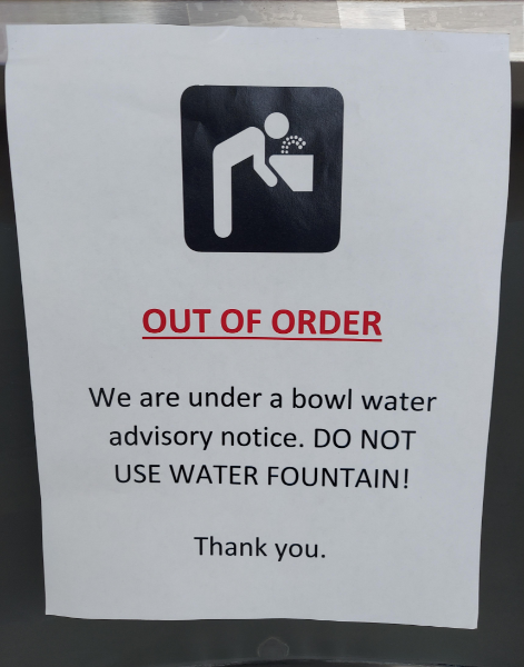 A sign with a graphic of a person drinking from a water fountain. The text reads: "OUT OF ORDER. We are under a bowl water advisory notice. DO NOT USE WATER FOUNTAIN. Thank you.