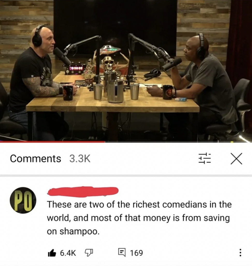 Two men are seated across from each other in a podcast studio, each with microphones and headphones. Both men have minimal or no hair. Beneath the video, a comment with numerous likes jokes that they are among the richest comedians due to saving on shampoo.