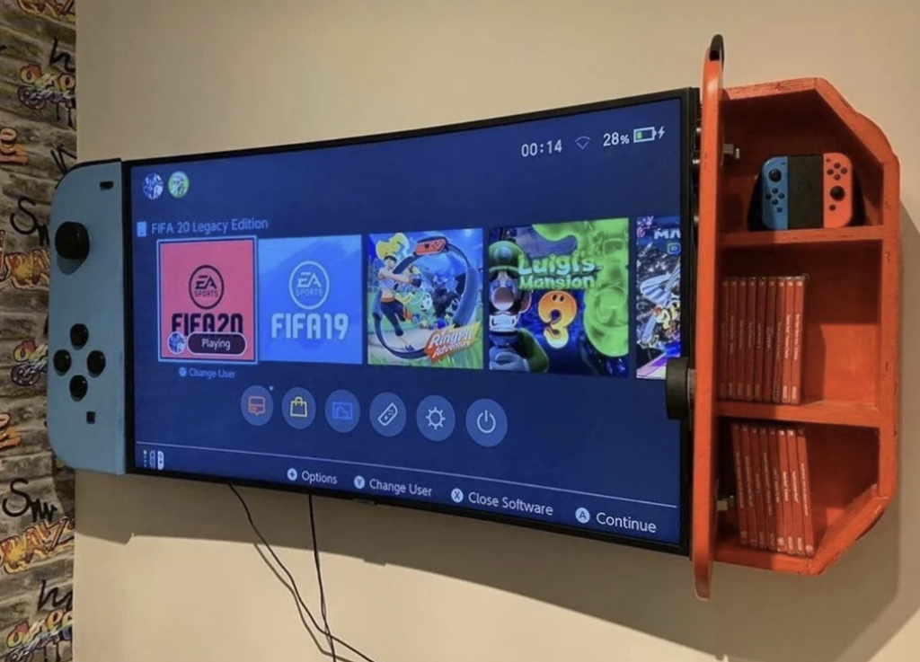 A flat-screen TV is encased in a large, blue console resembling a Nintendo Switch. It displays a gaming menu featuring titles like FIFA 20, FIFA 19, and Luigi's Mansion 3. To the right, a red shelf holds multiple game cases and two Nintendo Switch consoles.