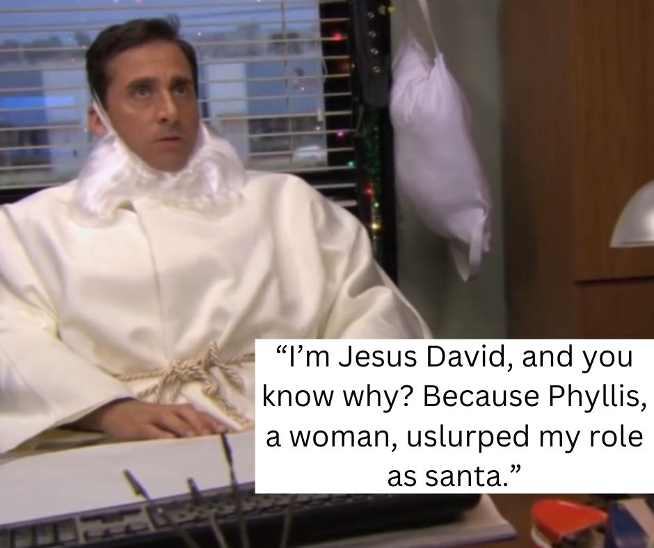 A man dressed in a white robe and fake white beard is sitting at a desk with a computer keyboard in front of him. He appears serious. The text overlay reads: “I’m Jesus David, and you know why? Because Phyllis, a woman, usurped my role as Santa.”