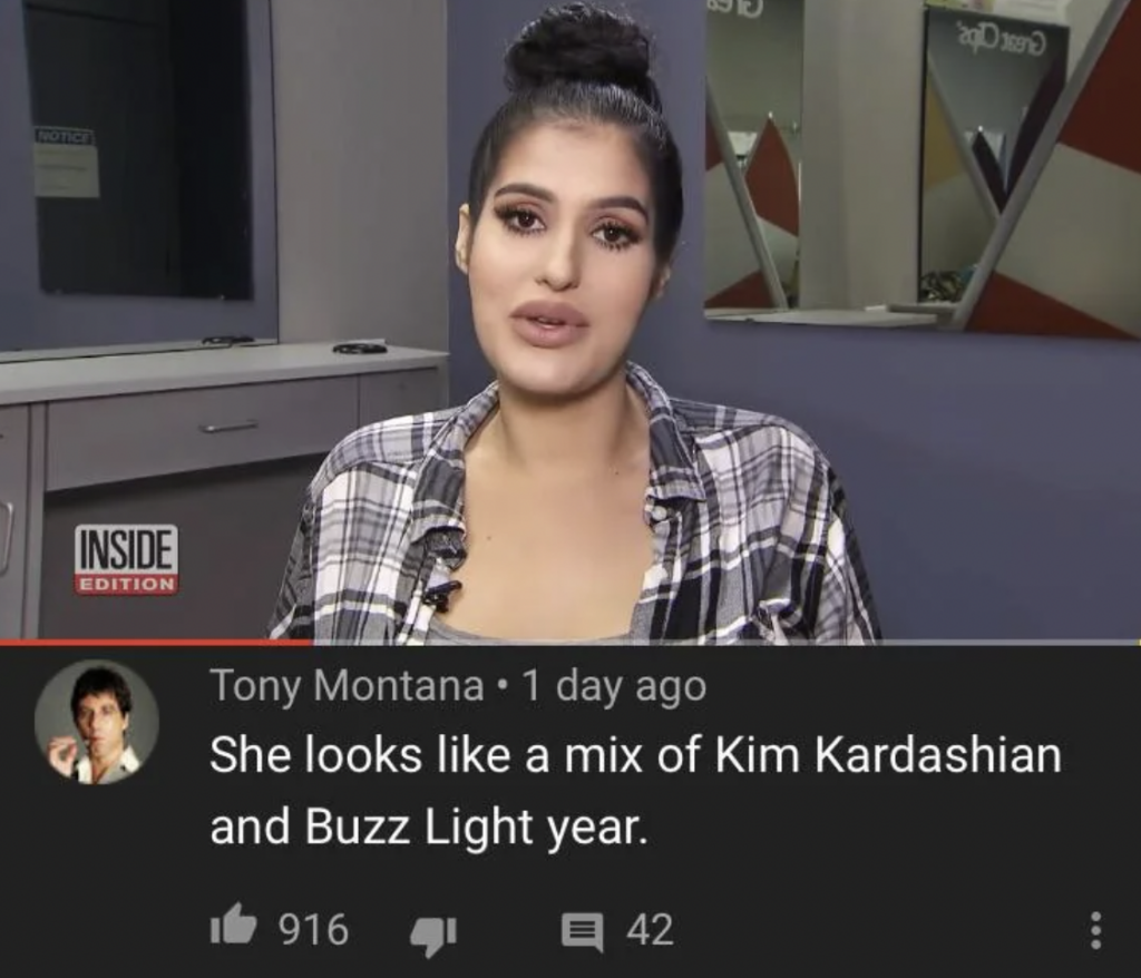 A woman with dark hair pulled into a bun is speaking in an interview room. She is wearing a plaid shirt. At the bottom, a YouTube comment says, "She looks like a mix of Kim Kardashian and Buzz Lightyear," with 916 likes and 42 replies.