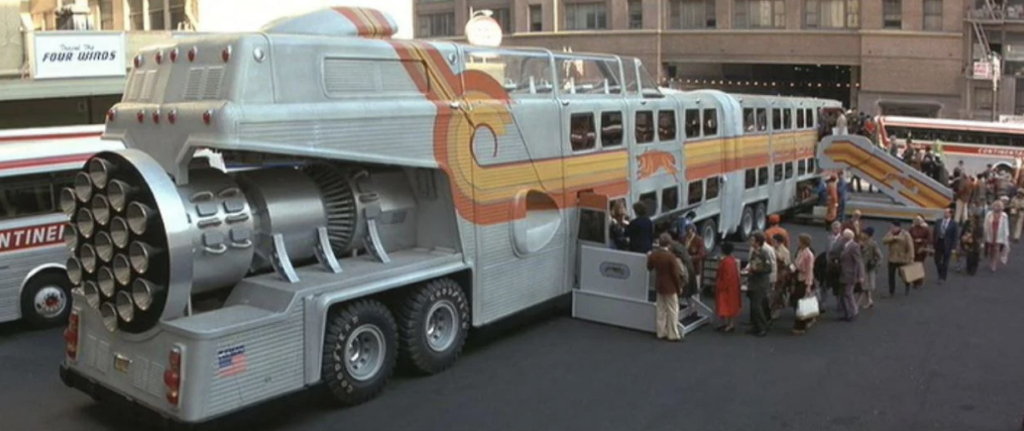 A large, futuristic bus with a jet engine-like rear and a silver and orange design is parked on a city street. A crowd of people is boarding the bus via a ramp with an overhead shelter. The scene appears to be in the 1970s, based on the fashion and bus design.