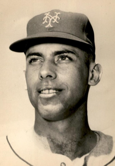 A black and white photograph of a baseball player wearing a cap with a monogrammed logo and a jersey. The player is looking slightly to the left with a neutral expression. The image appears to be from the mid-20th century.