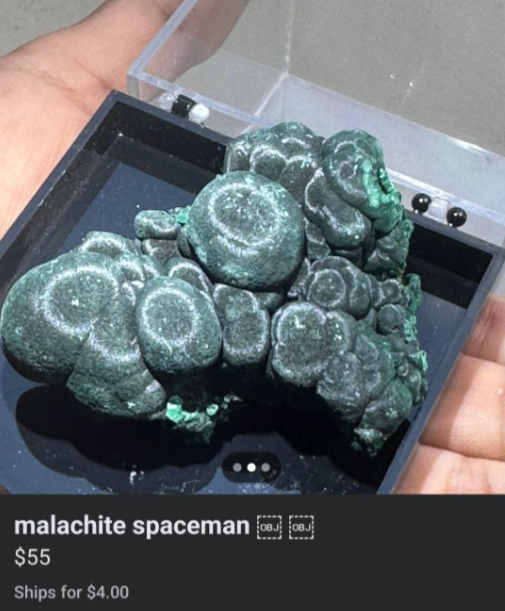 A hand holds a display case with a green malachite mineral specimen inside. The malachite has a textured, bubbly surface. Text below the image reads: "malachite spaceman $55 Ships for $4.00.