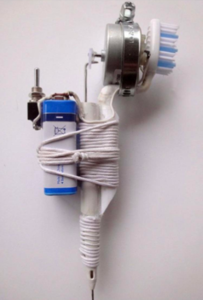 A homemade tattoo machine consisting of a toothbrush head, a small motor, a switch, a battery, and a white handle with thread wrapped around it. The components are assembled in a compact design with wires connecting the parts.