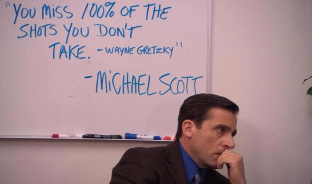 A man in a suit sits thoughtfully in front of a whiteboard that reads, "You miss 100% of the shots you don't take. - Wayne Gretzky - Michael Scott.