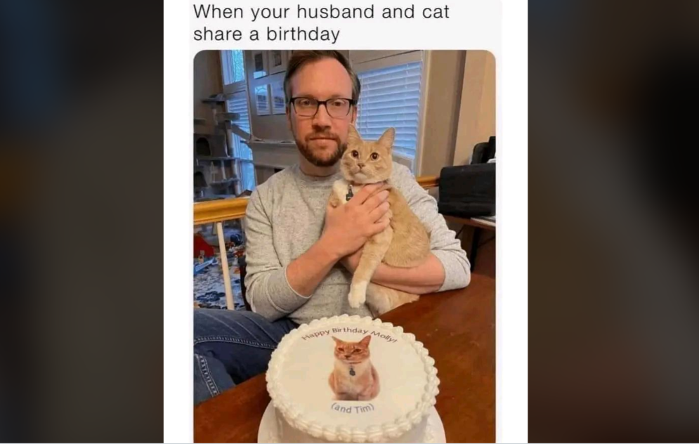 A man with glasses holds an orange cat while seated at a table. In front of them is a white cake with an image of the same cat wearing a bow tie. Text on the cake reads, "Happy Birthday Andrew (and Tim)." The caption above reads, "When your husband and cat share a birthday.