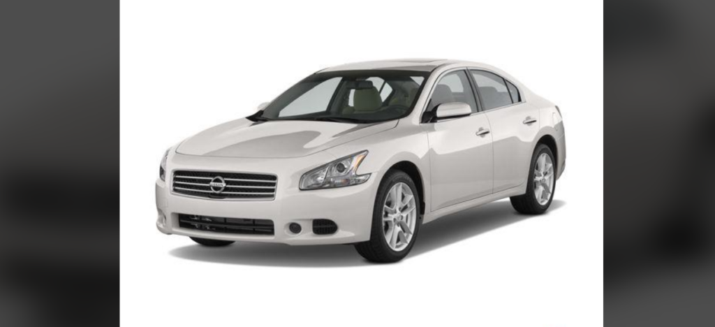 A sleek white sedan with a modern design is parked on a plain white background. The car has a smooth, curvy body, stylish front headlights, and alloy wheels. The grill features a prominent logo in the center. The windows are slightly tinted.