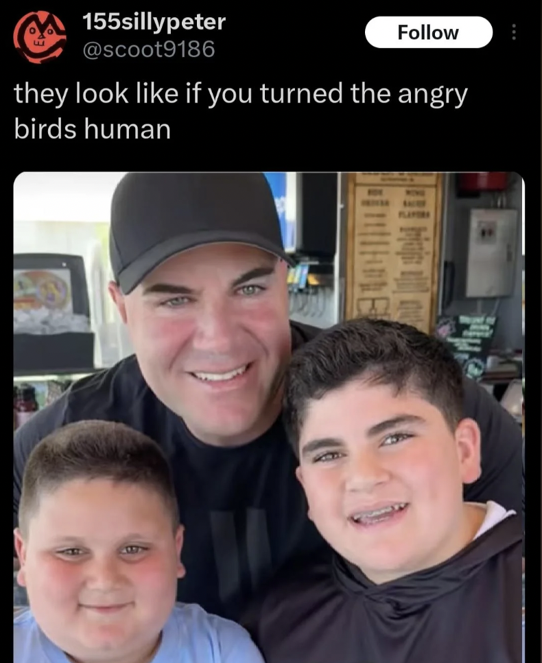 A man in a black cap and black shirt poses with two smiling boys in a casual setting. The man is in the middle, with the boys on either side of him. The tweet caption above the image reads, "they look like if you turned the angry birds human.